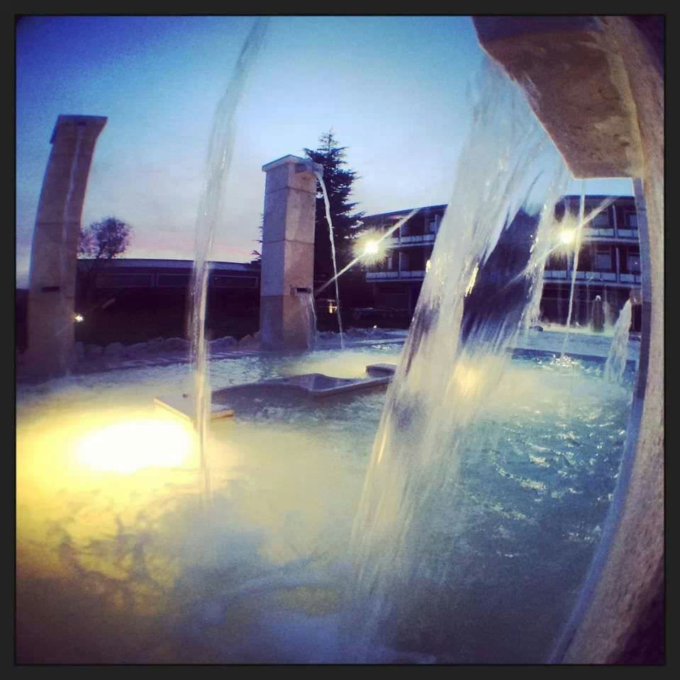 Fontana con getti d'acqua illuminati al tramonto.