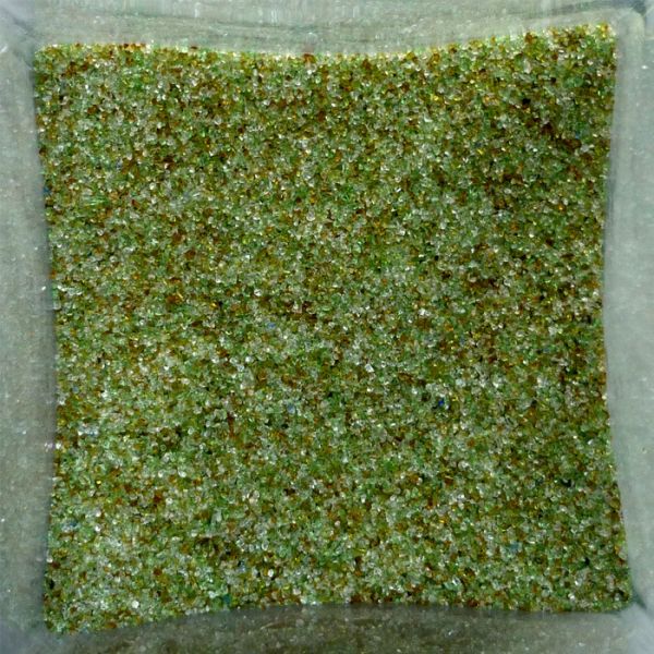 Granelli di sabbia verde in un contenitore trasparente.