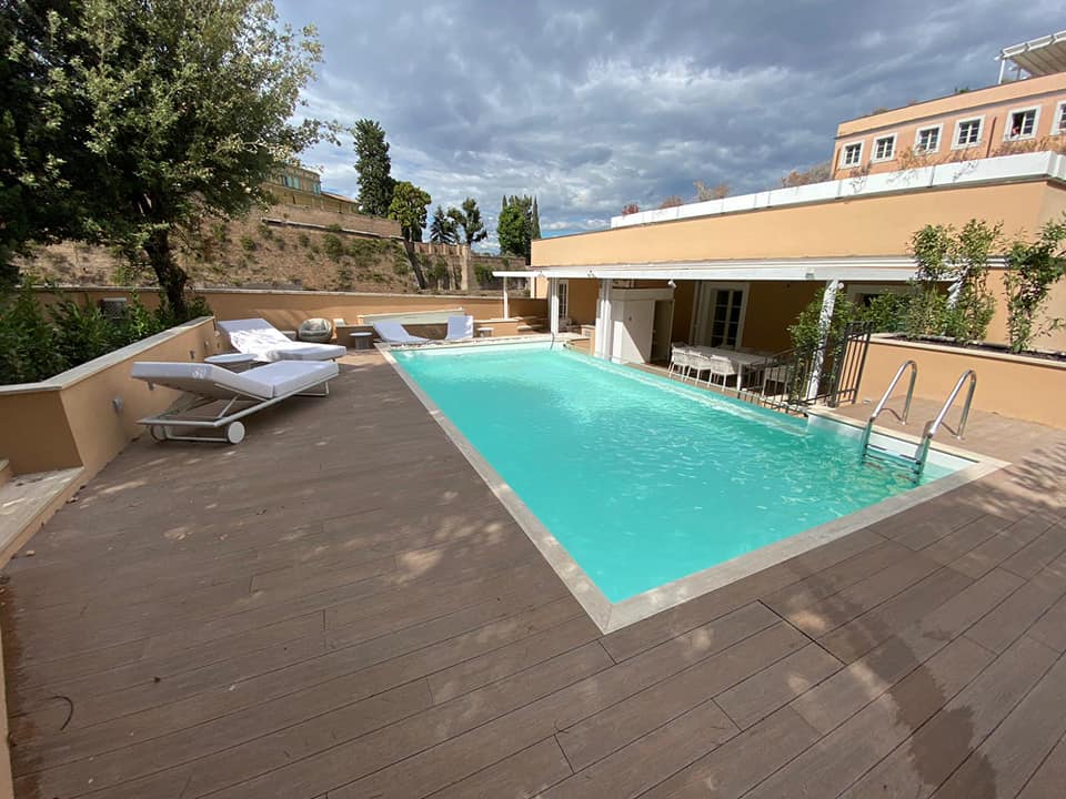 Piscina all'aperto con lettini e cielo nuvoloso.
