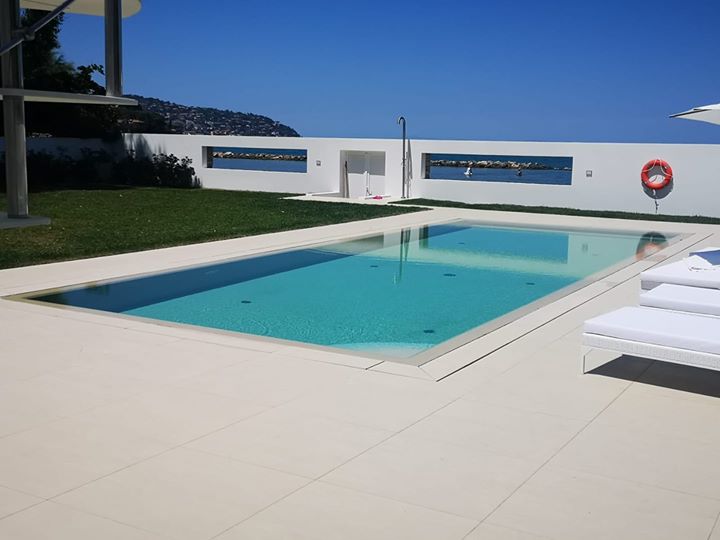 Piscina all'aperto con vista sul mare e sdraio.
