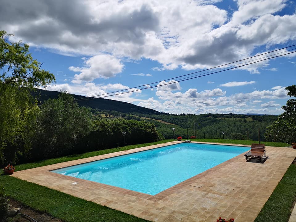 Piscina all'aperto con vista su colline verdi.