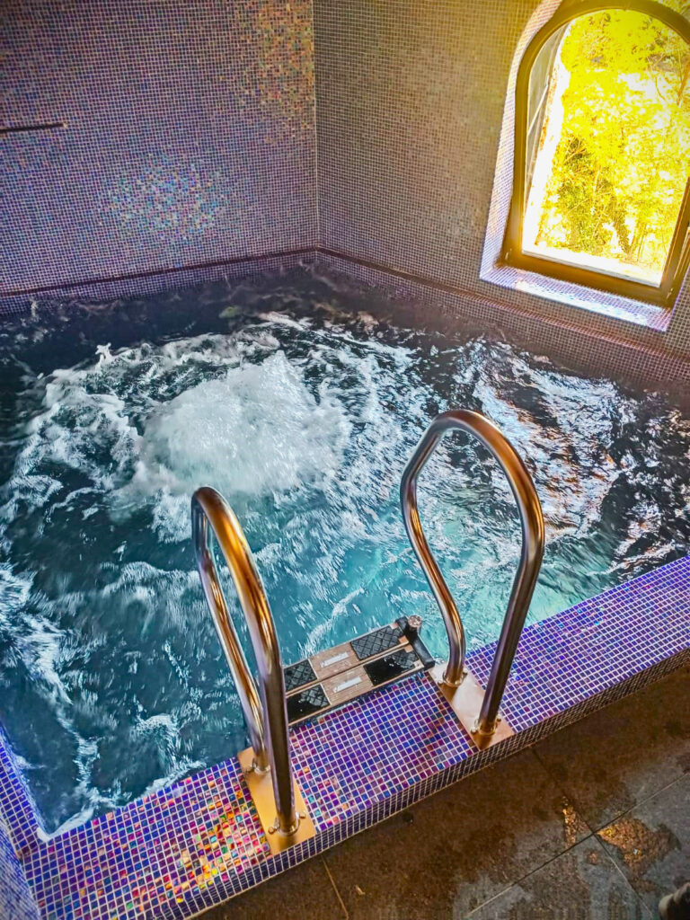 Vasca idromassaggio interna con mosaico e finestra.