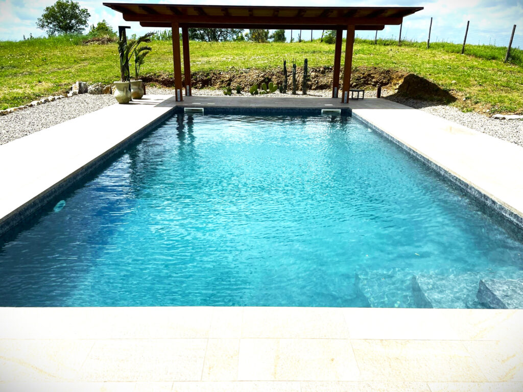 Piscina all'aperto con pergola e piante decorative.