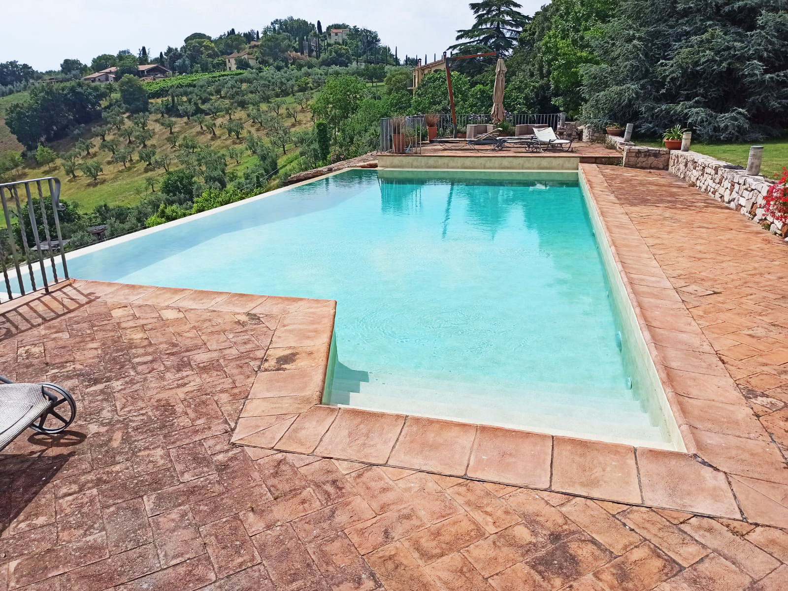 Piscina a sfioro con vista su colline alberate.