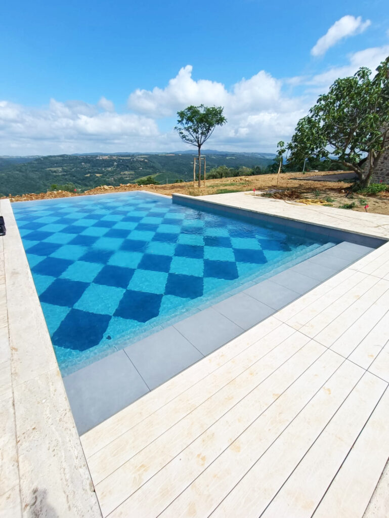 Piscina con motivo a scacchi, vista panoramica collinare.