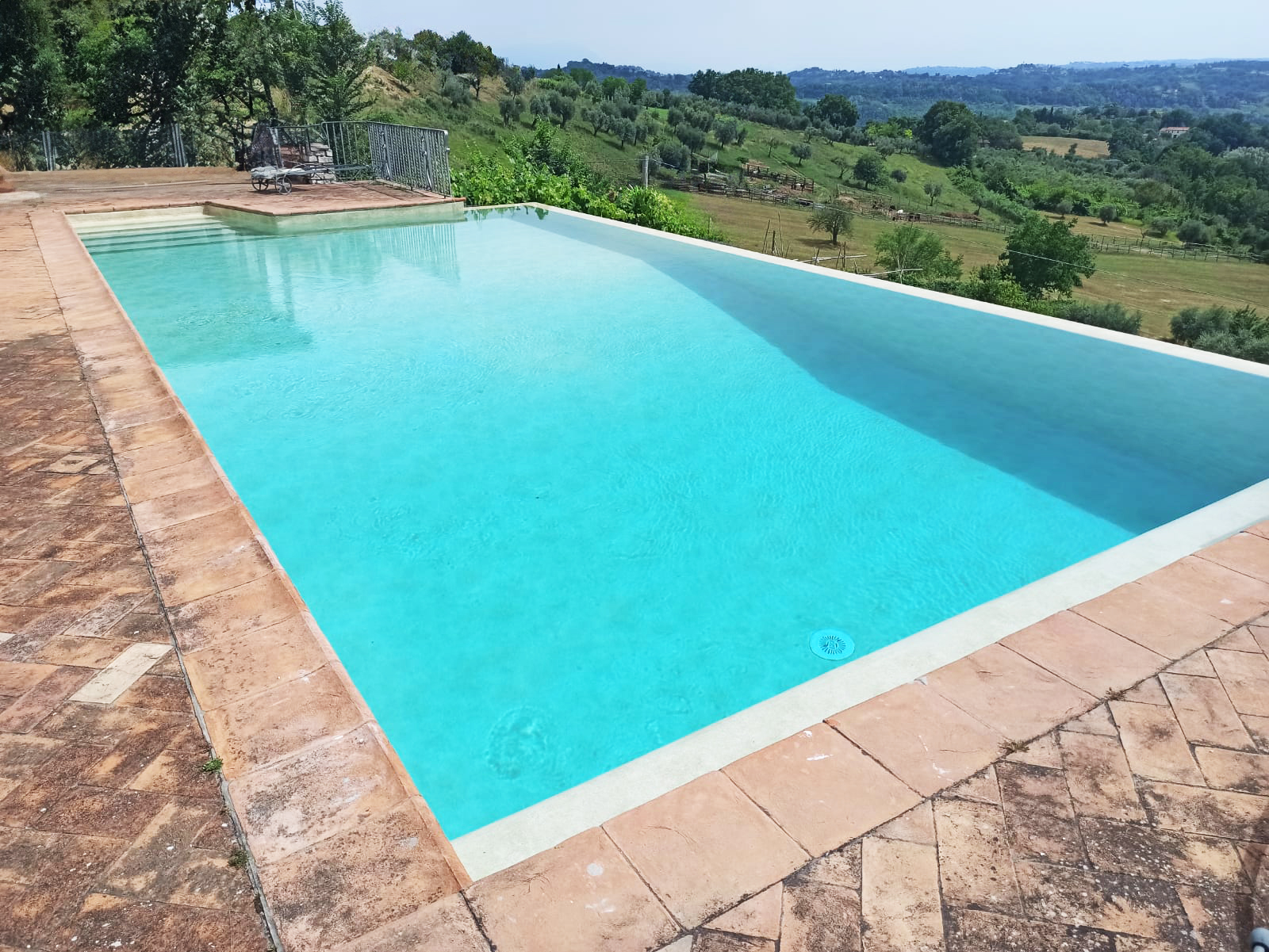 Piscina a sfioro con vista su colline verdi.